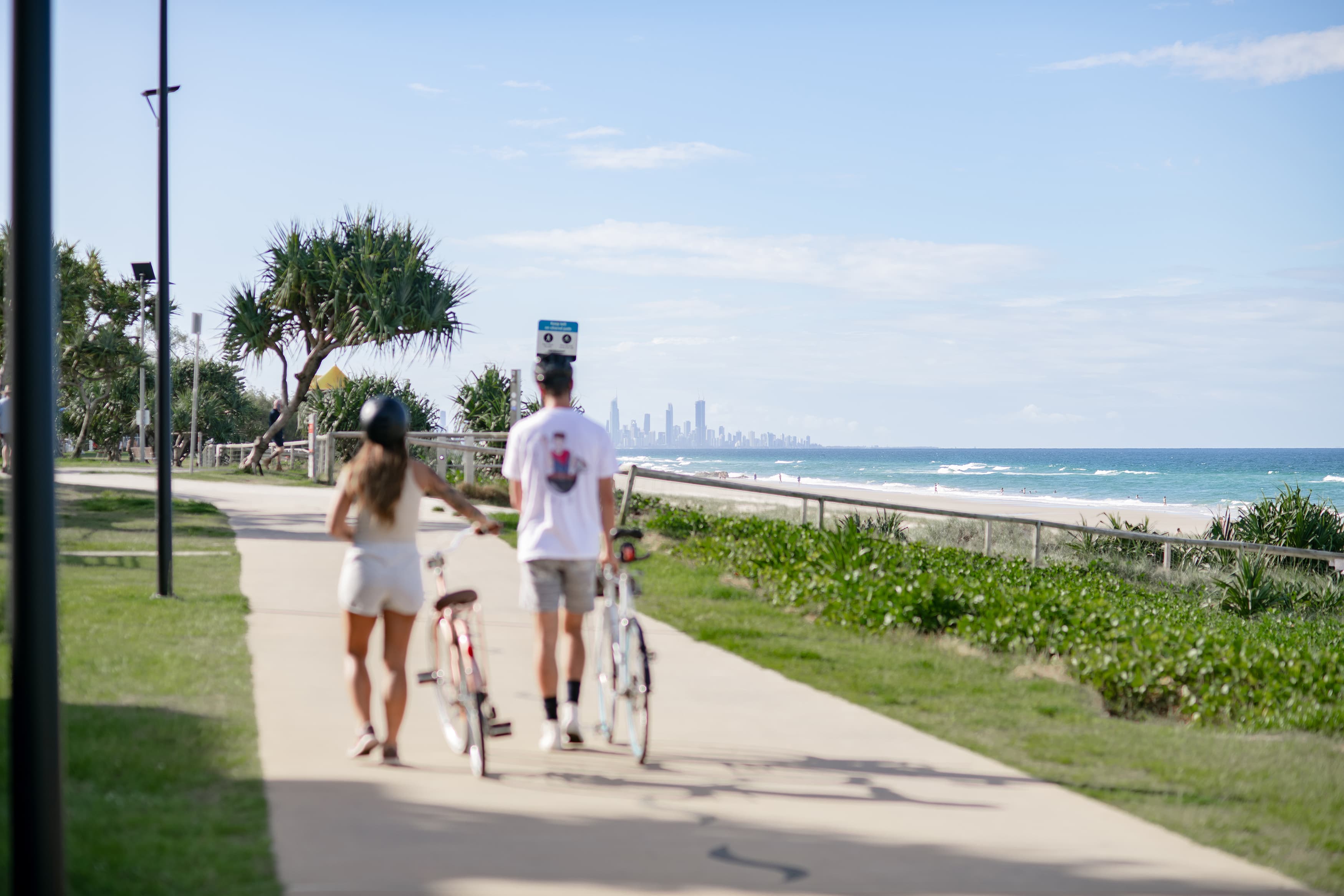 A woman and man walking their bikes along a path.