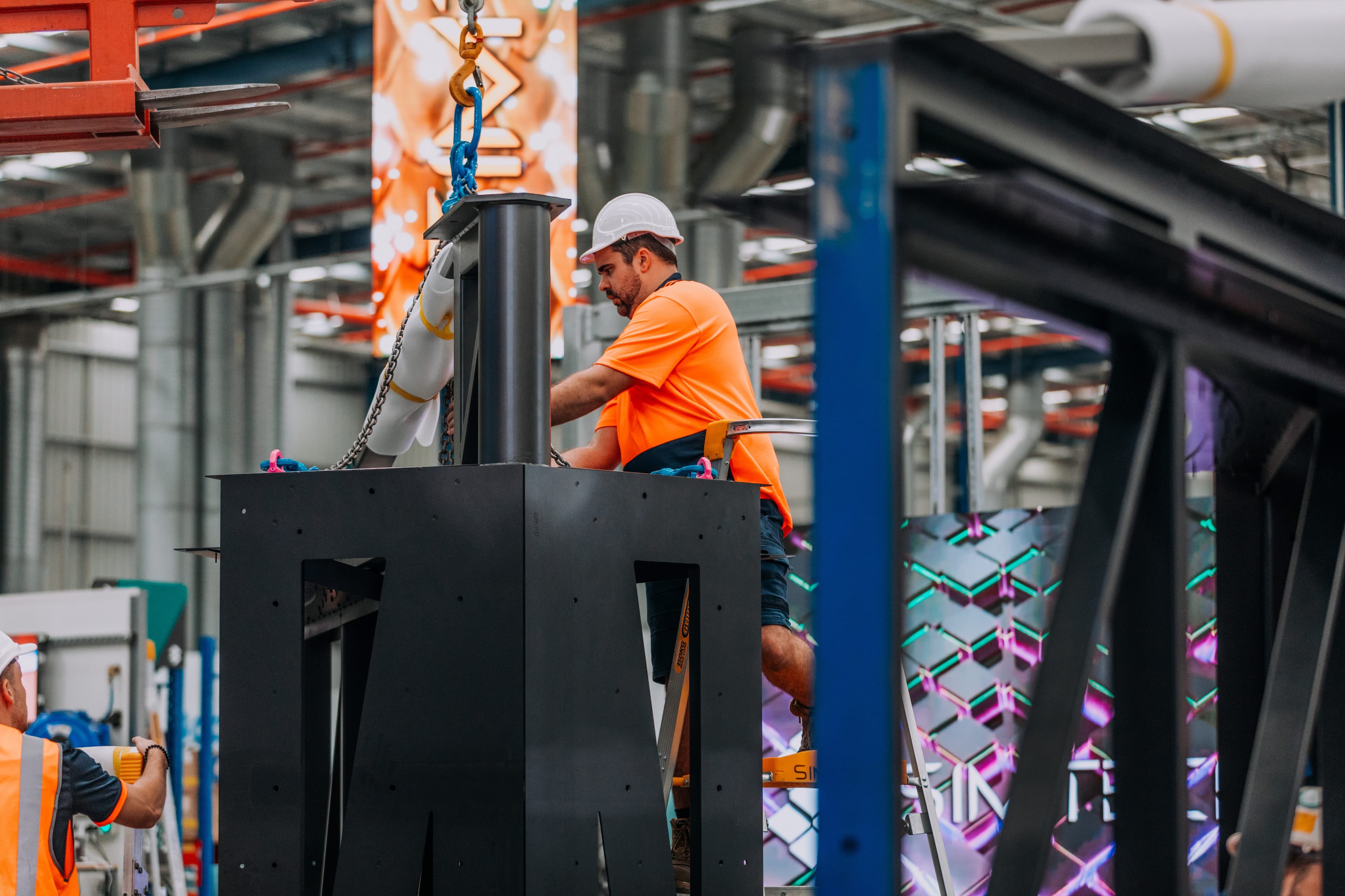Factory worker assembling large-scale LED screen.