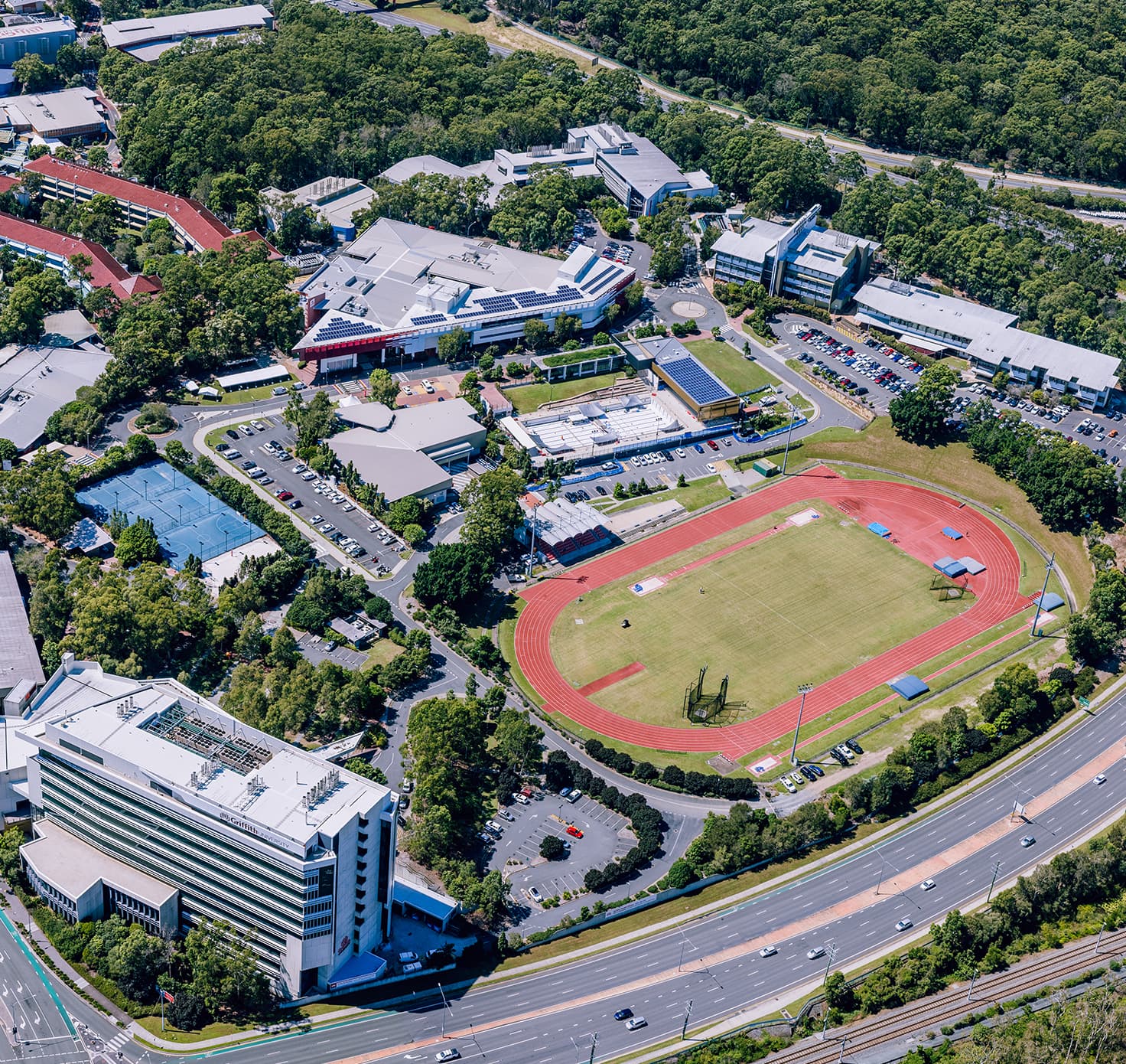 An aerial of a track field, tennis court and buildings.
