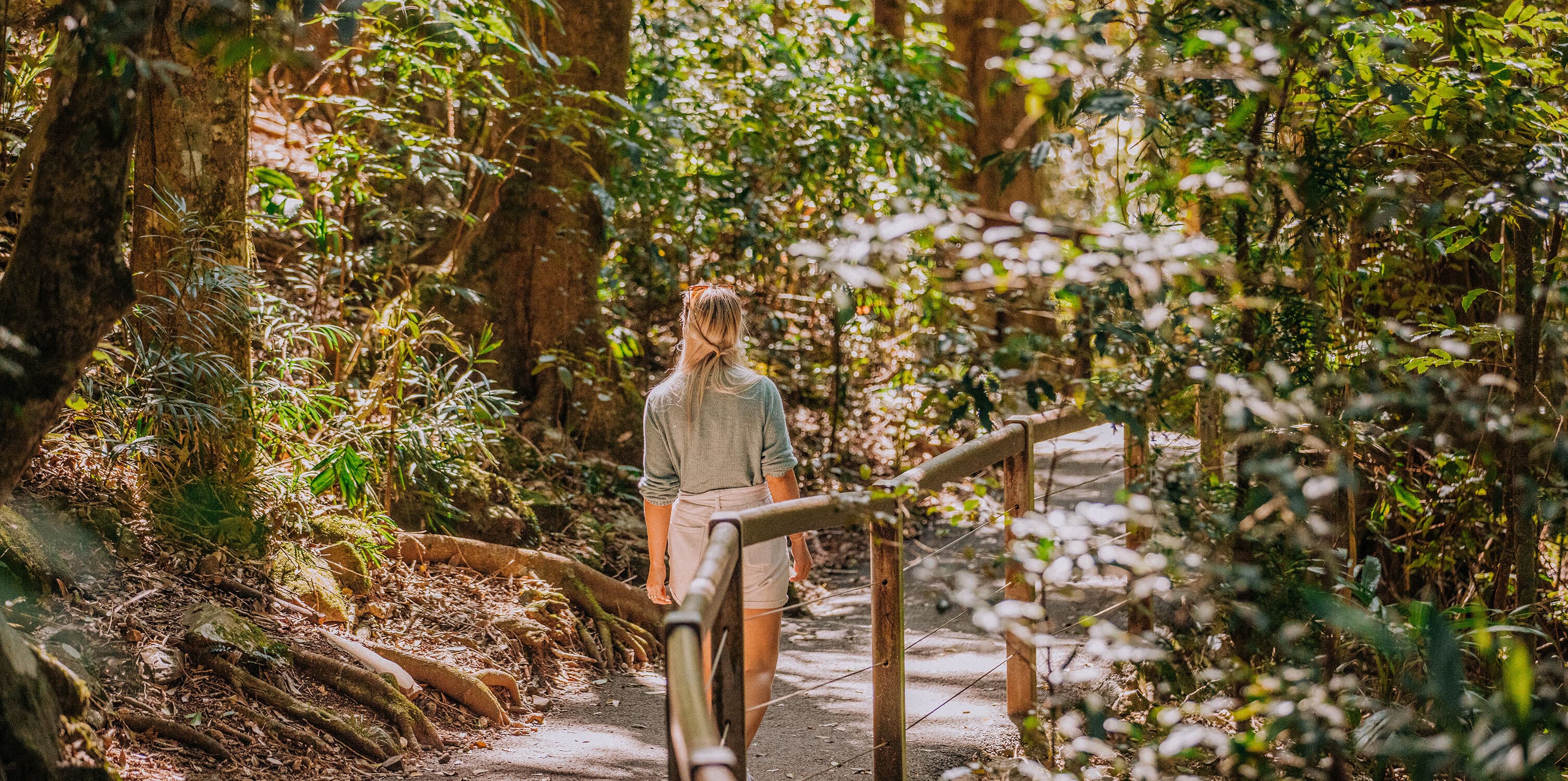 Woman walks along path through forest.