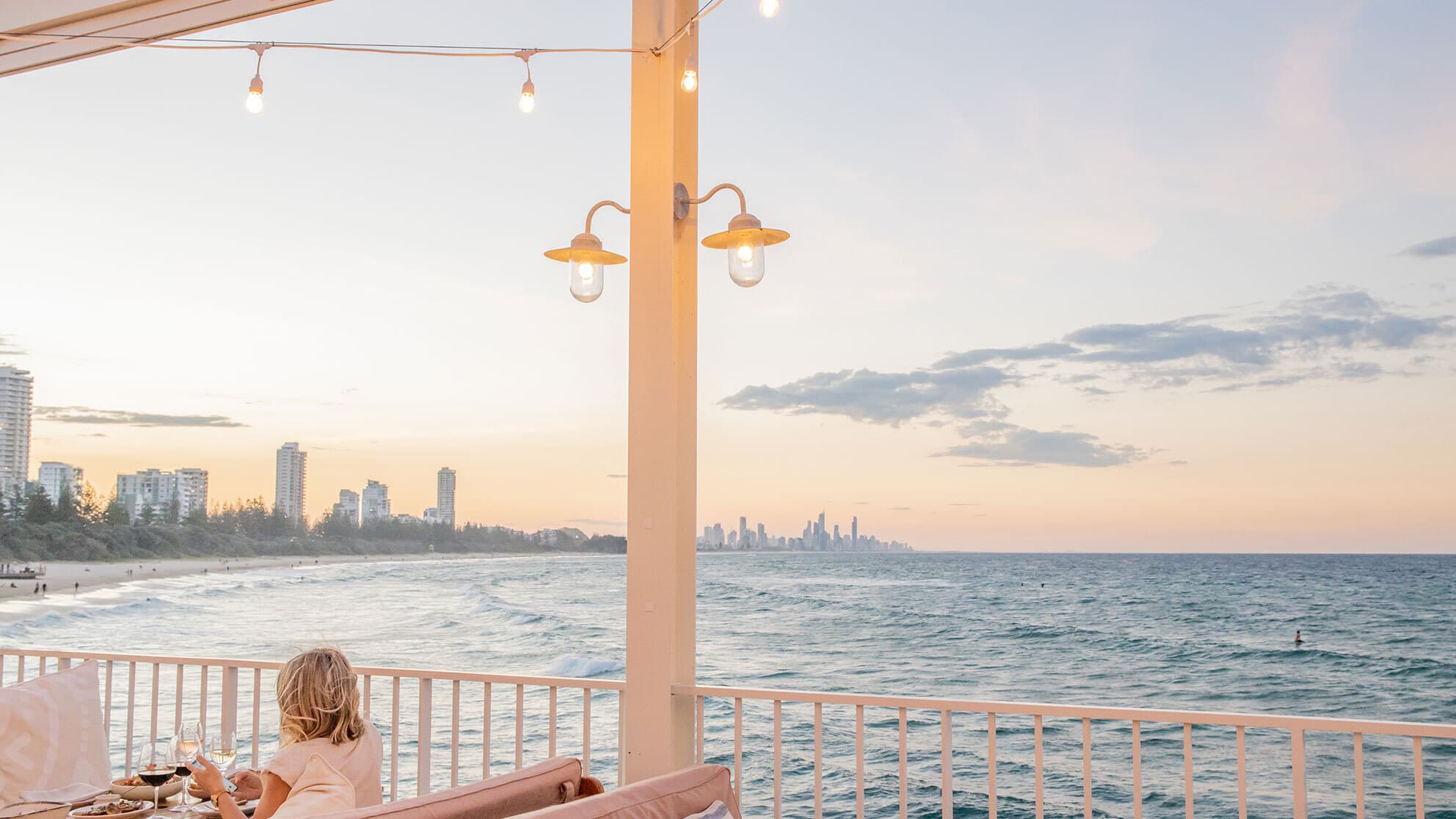View over the ocean at sunset from a restaurant table.