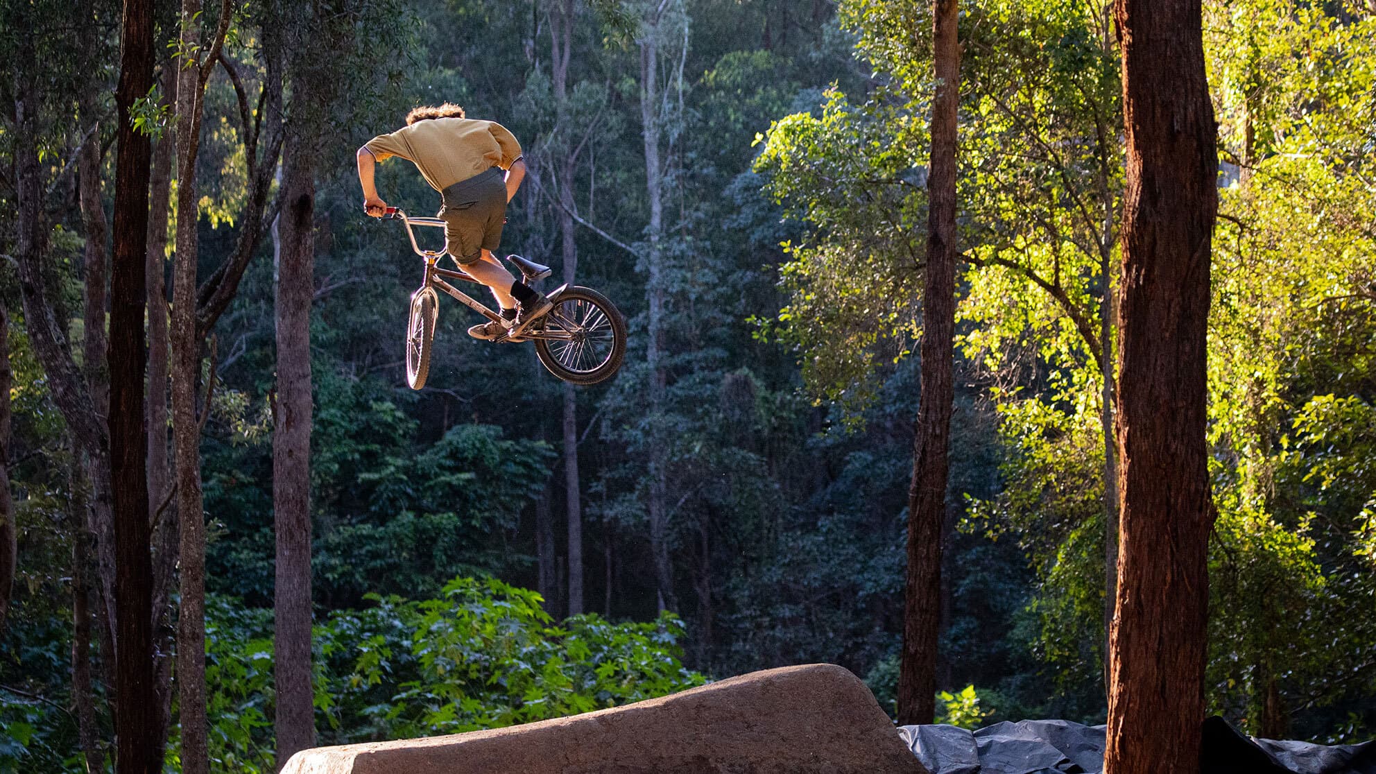 A mountain biking man makes a jump from a ramp on the track.