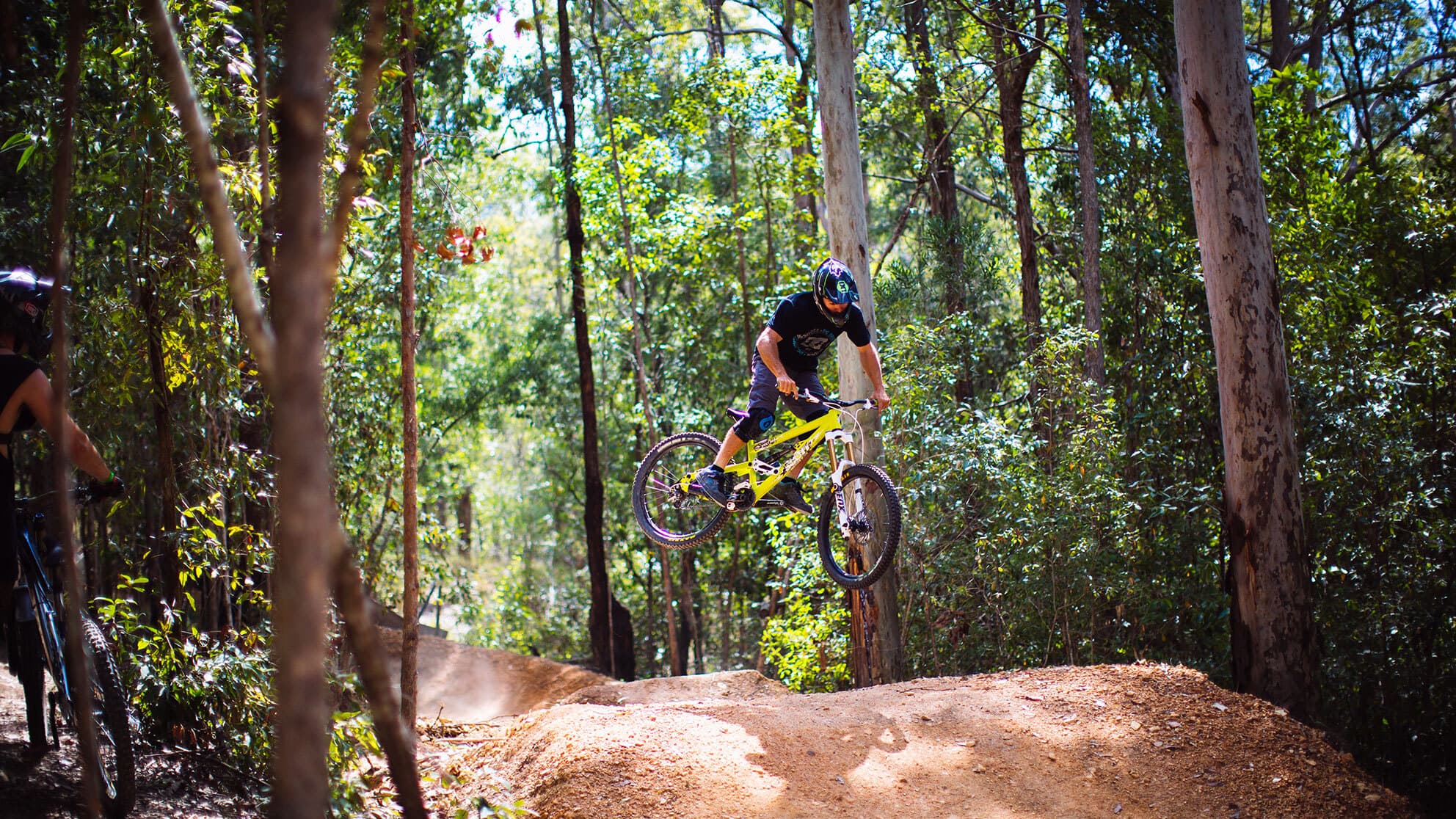 A mountain biking man makes a jump from a ramp on the track.