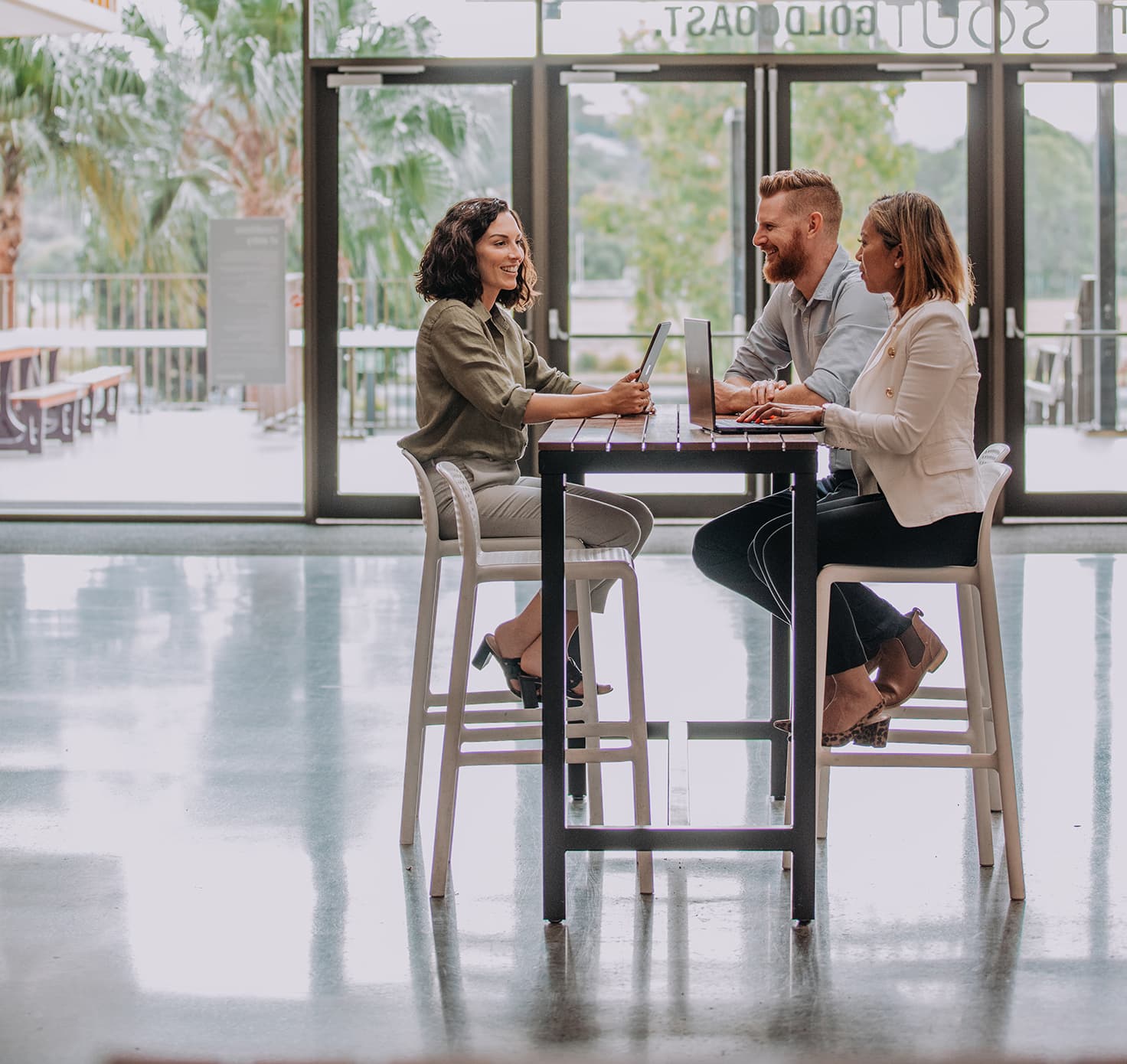 Three professional people sit at a table in happy conversation.