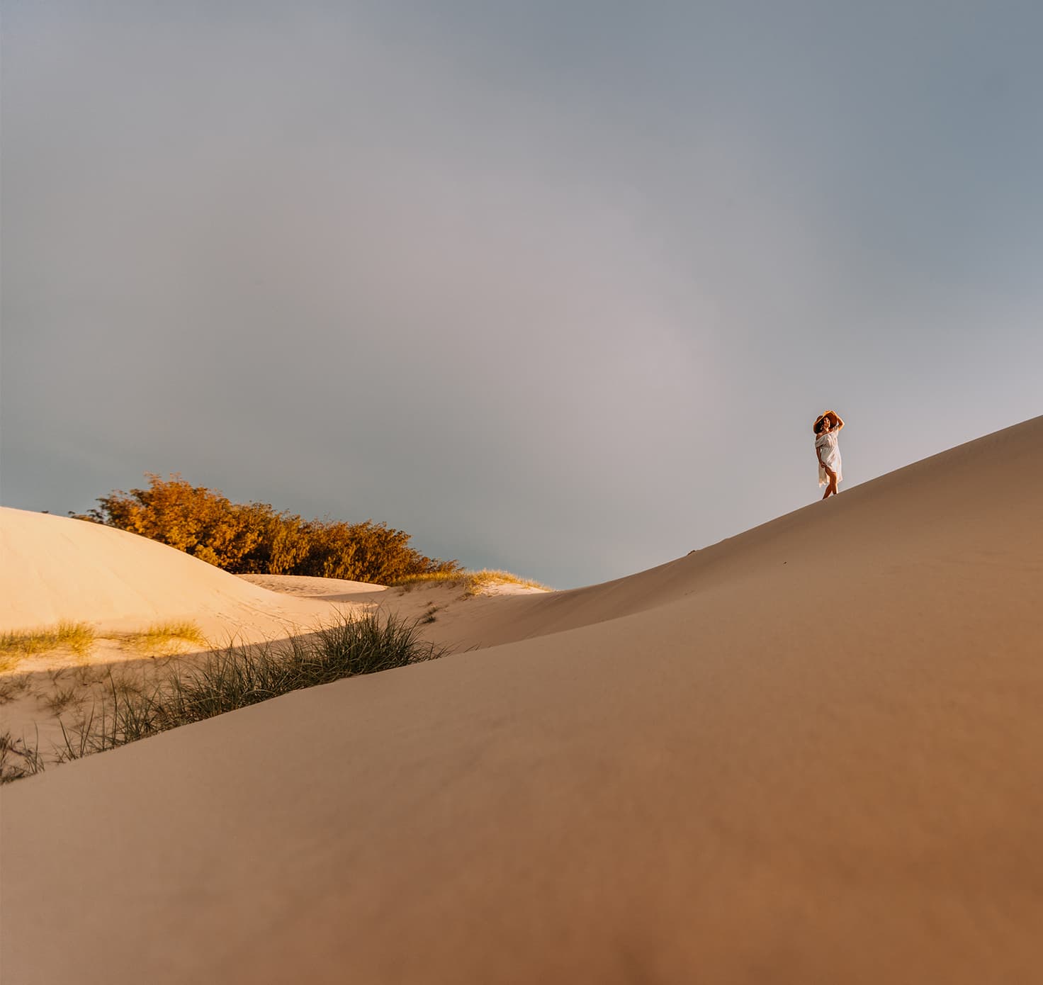 A woman walking along sand dunes.